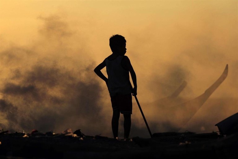 Uno dei tanti “figli delle discariche” tra il fumo dei rifiuti bruciati a Manila, nelle Filippine - Ansa